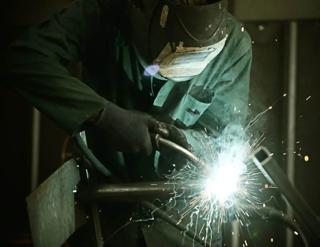 Welder with protective mask welding metal and sparks